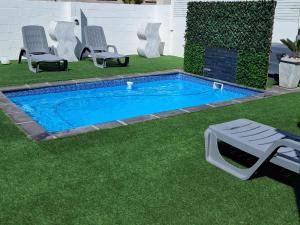 a small swimming pool with chairs and a table in a yard at Beach Style Cottage in Langebaan