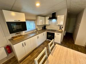 a kitchen with white cabinets and a sink and a tv at Chalet Jersey in Lauwersoog +24 photos