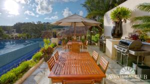 a patio with tables and umbrellas next to a pool at Aventuras Club in Puerto Aventuras