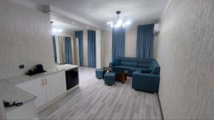 a living room with a blue couch and a kitchen at Toshkent Hotel in Andijan