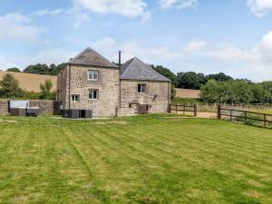 an old stone house with a large grass field at The Granary at Henrhiw Farm Cottages in Usk