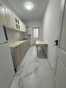 a kitchen with marble floors and white cabinets and a table at Garsonieră in Chiajna