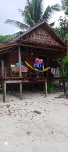 a hut on the beach with a bench and a tv at Napoleon Homestay Raja Ampat in Poelau Mansoear +1 photo