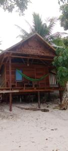 a small hut on the beach with a palm tree at Napoleon Homestay Raja Ampat in Poelau Mansoear