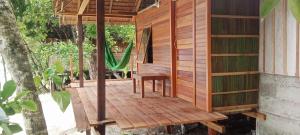 a wooden deck with a bench and a hammock at Napoleon Homestay Raja Ampat in Poelau Mansoear