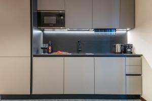 a kitchen with white cabinets and a microwave at HelloCHALET - Front Row with balcony overlooking the Cretaz slopes in Breuil-Cervinia