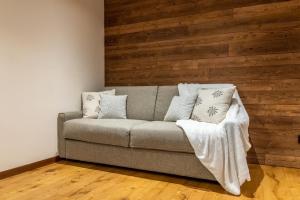 a couch in a room with a wooden wall at HelloCHALET - Front Row with balcony overlooking the Cretaz slopes in Breuil-Cervinia