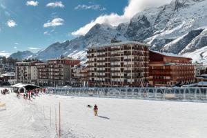 a group of people in the snow in front of buildings at HelloCHALET - Front Row with balcony overlooking the Cretaz slopes in Breuil-Cervinia +35 photos