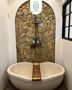 a bath tub in a room with a stone wall at Sampai Villa Prambanan in Randugunting