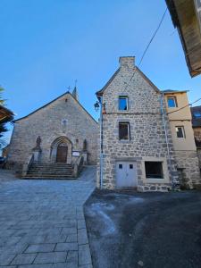 a large stone building with a church in the background at 16 Chemin De Compostelle in Sénergues