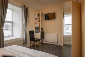 a bedroom with a bed and a chair and a television at The Trout Fly Guest House in Port Ellen