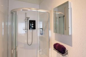 a shower with a glass door and a mirror at The Trout Fly Guest House in Port Ellen +25 photos