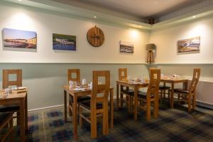 a restaurant with wooden tables and chairs and a clock at The Trout Fly Guest House in Port Ellen