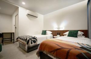 a hotel room with two beds with green pillows at Palma Hotel in Bangkok