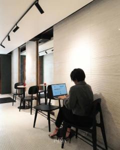 a woman sitting on a chair with a laptop at Palma Hotel in Bangkok