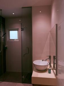 a bathroom with a sink and a glass shower at Poshpack Skyline Hostel in Kuala Lumpur