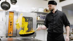 Ein Mann bereitet in einer Küche Essen im Ofen zu. in der Unterkunft Valjeviken in Sölvesborg