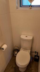 a white toilet in a bathroom with a window at Winner in the Overberg in Bredasdorp