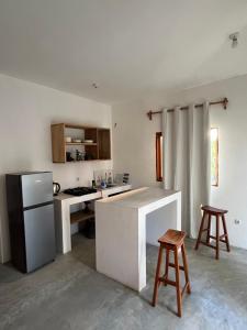 Eine Küche mit Kühlschrank und einer Theke mit zwei Hockern in der Unterkunft Kategha Beach Guesthouse in Praia do Tofo + 23 Fotos