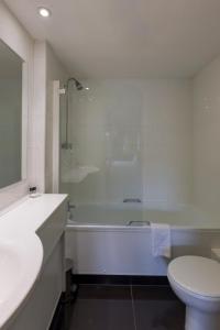 a bathroom with a tub and a toilet and a sink at Lakeside International Hotel in Camberley +84 photos