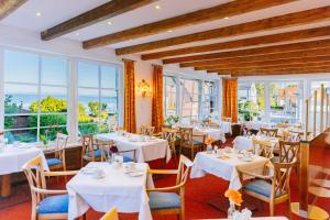 a restaurant with white tables and chairs and windows at Hotel Seeperle in Langenargen
