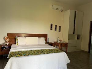 a bedroom with a large bed and a night stand at Nhambavale Niara House in Chidenguele