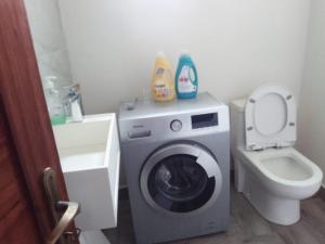 a bathroom with a washing machine and a toilet at Nhambavale Niara House in Chidenguele