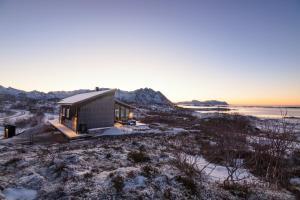 a house on a hill with the sunset in the background at Fredheim, Northern Light Lodge in Laukvik