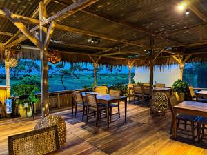 a restaurant with tables and chairs on a wooden deck at MareCoves Resort & Glamping in Cilangkahan