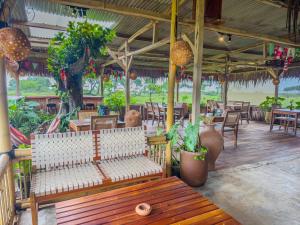 a bench in a restaurant with tables and chairs at MareCoves Resort & Glamping in Cilangkahan