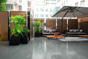 a patio with couches and an umbrella and plants at Orange Crystal Hotel Nanjing Museum in Nanjing