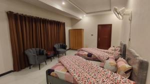 a bedroom with two beds and chairs in a room at Hotel 26 in Islamabad +2 photos