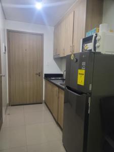 a kitchen with a black refrigerator and wooden cabinets at Staycation in Tropez 924 in Manila