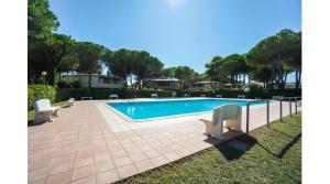 a swimming pool with two white chairs next to it at Tivoli in Bibione +12 photos