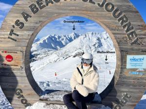 a man sitting on a bench in front of a mountain at Wallackhaus RegioJet Hotels in Heiligenblut