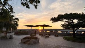 a sunset with tables and umbrellas and a bridge at Hotel GALA Naha's only sandy beach front all rooms oceanview in Naha