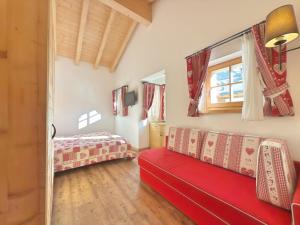 a living room with a red couch and a bed at Cesa Dolomia Apartments in Canazei