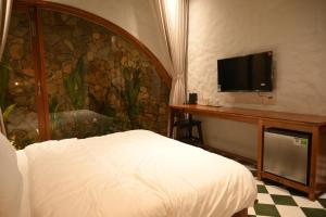 a bedroom with a bed and a desk with a flat screen tv at Berry Boutique in Hue
