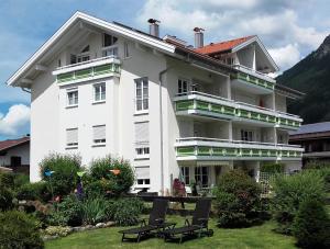 ein großes weißes Gebäude mit zwei Stühlen im Hof in der Unterkunft Alpenflair Ferienwohnungen Whg 301 in Oberstdorf