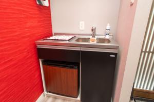 a small kitchen with a sink and a red wall at 三十三Tsuki in Kyoto