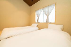 two beds in a room with a window at 三十三Tsuki in Kyoto