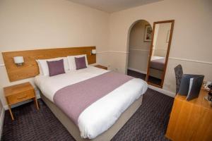 a hotel room with a large bed and a mirror at The Fountain in Soham