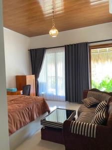 a bedroom with a bed and a couch and a glass table at Raya Homestay in Kuta Lombok