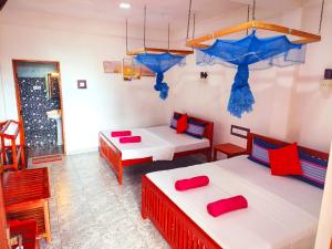 two beds in a room with red and blue pillows at Eco Diamond Palace in Ella