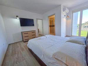 a white bedroom with a large bed and a flat screen tv at GHouse in Gallipoli