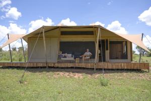 two people sitting in a tent in a field at Anantya Serengeti in Serengeti