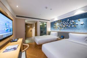 a hotel room with two beds and a flat screen tv at Orange Crystal Hotel Nanjing Museum in Nanjing