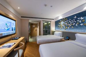 a hotel room with two beds and a flat screen tv at Orange Crystal Hotel Nanjing Museum in Nanjing