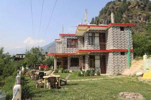 a house with chairs and a table in the yard at backpacker's stop in Jagatsukh