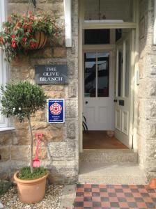 una señal en el lateral de un edificio con una puerta en The Olive Branch, en St Ives
